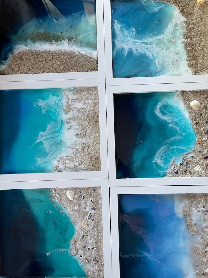 Finished white-framed resin ocean originals — teal waves meeting real Cornish sand and shells.