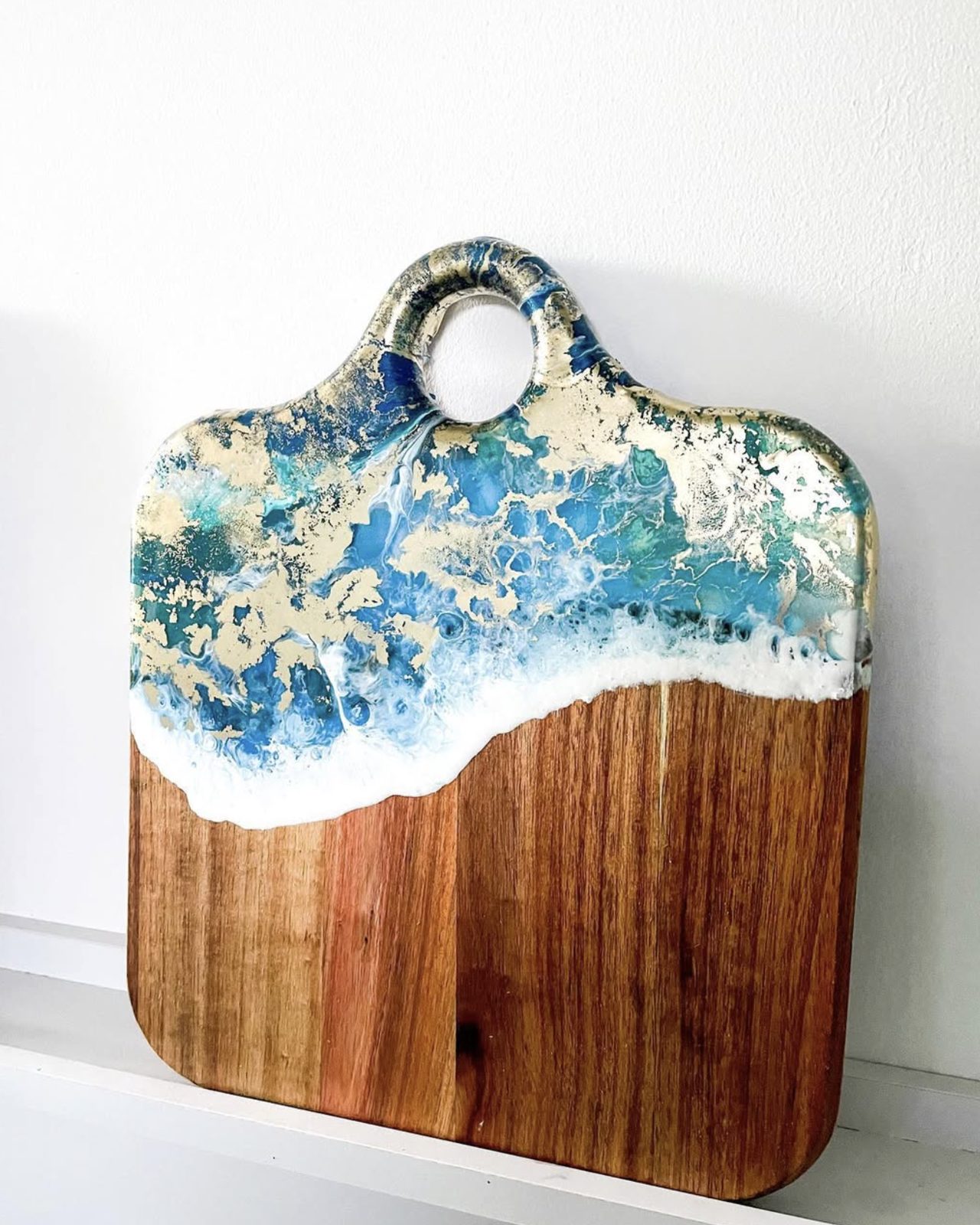A serving board with gold leaf set into the resin wave.
