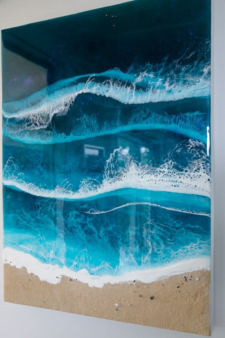 A finished resin ocean piece, teal waves over real sand.