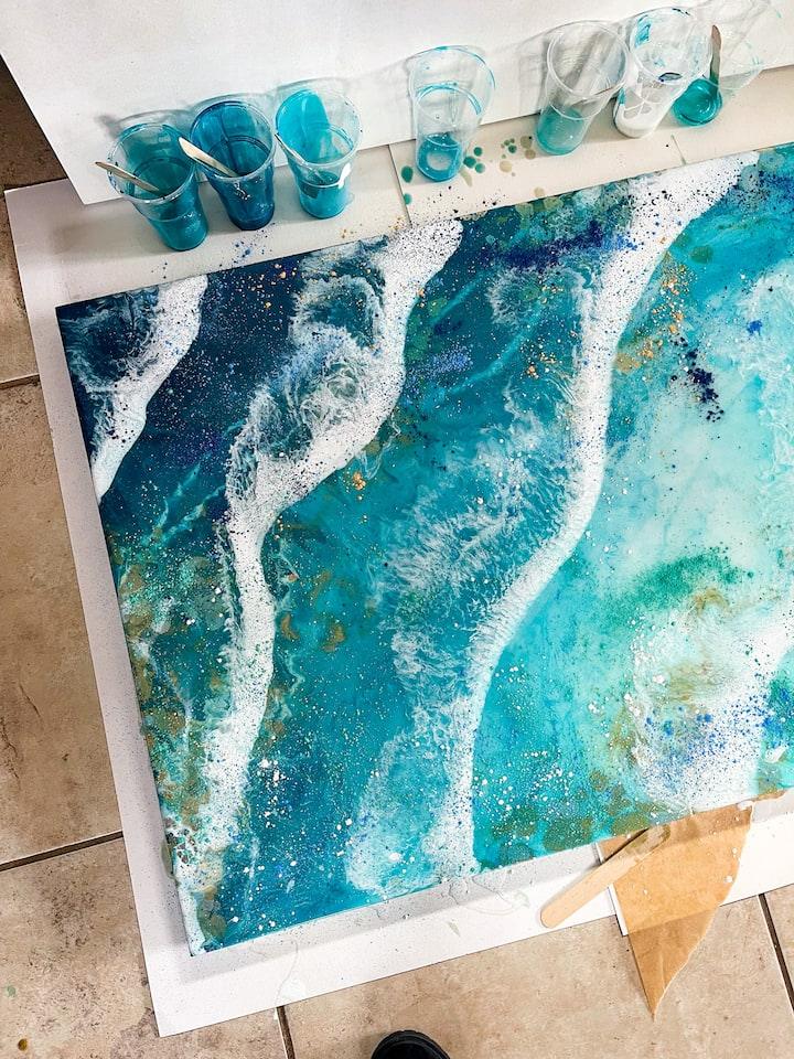Large-scale resin ocean artwork in progress — teal waves with gold flecks.