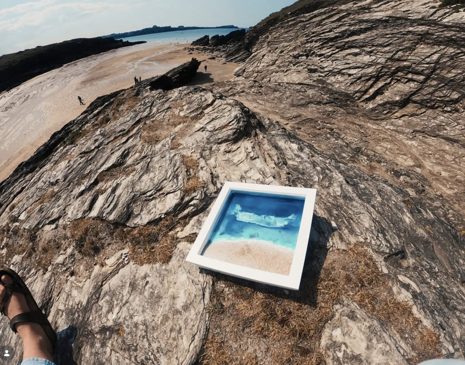 A resin ocean piece propped on the rocks above the surf.