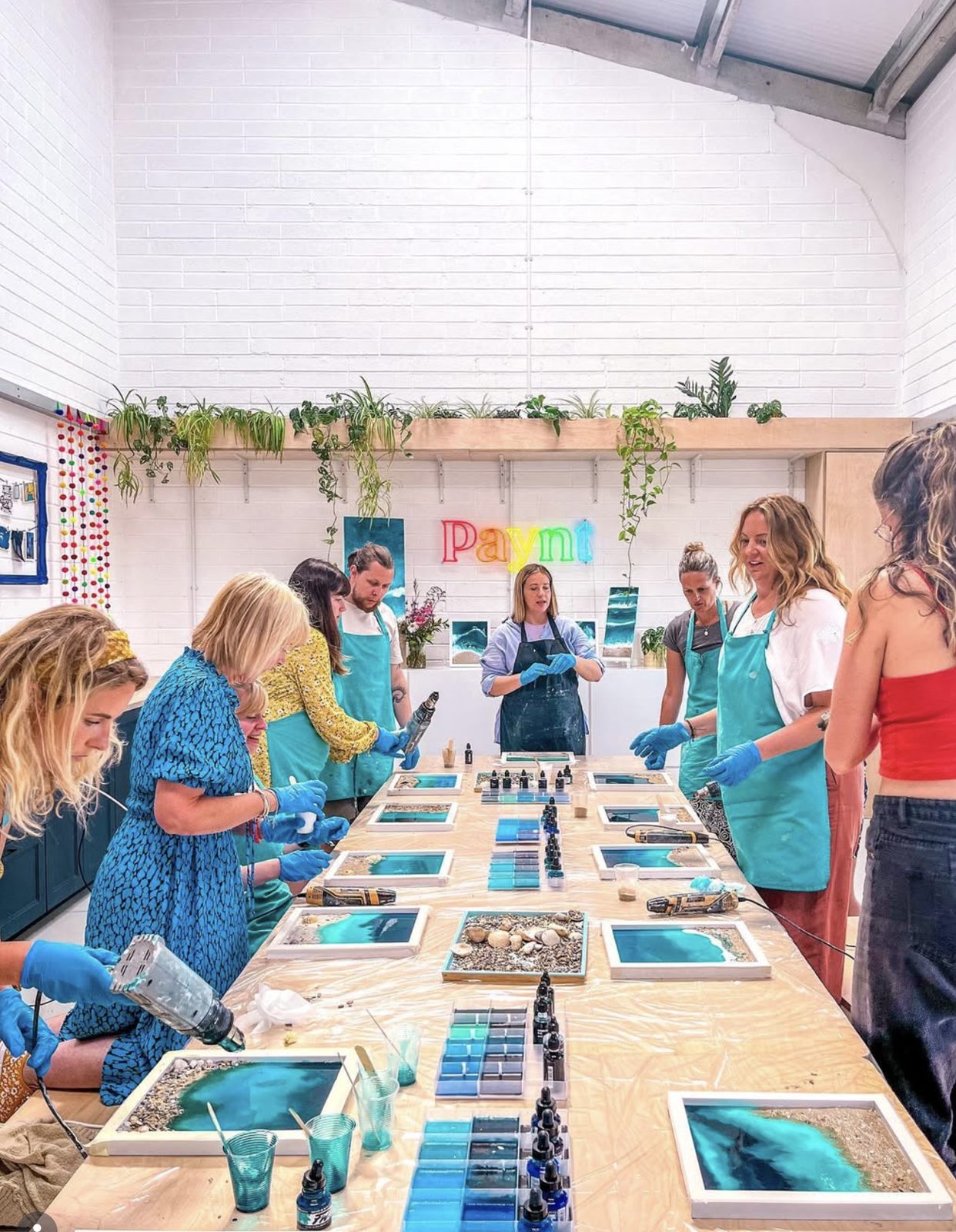 A workshop in full swing — six guests around the studio table, aprons on, oceans in progress.